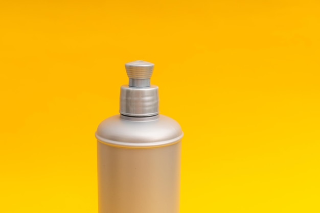 Zdjęcie szara butelka szamponu na żółtym tle