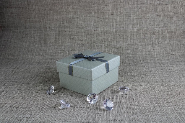 Zdjęcie szare pudełko upominkowe z przezroczystymi kryształkami na szarym tle