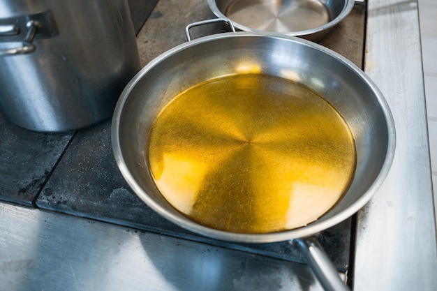 Szare stylowe aluminiowe naczynia na kuchence w jadalni Okrągła patelnia jest wypełniona olejem roślinnym lub tłuszczem
