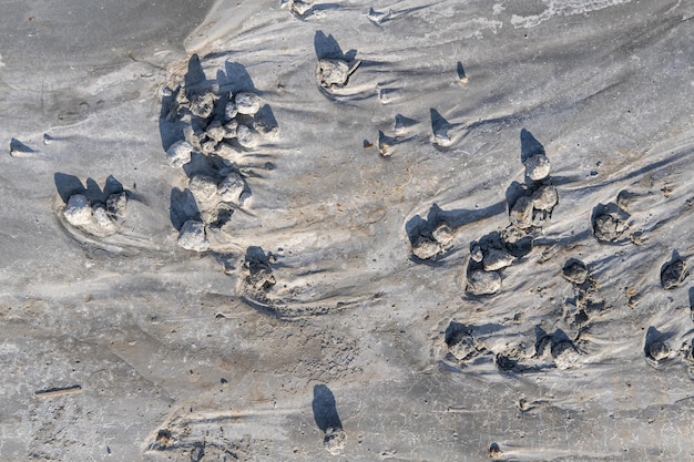 Szare tło spękanej cementowej zestalonej zaprawy przeplatane ziarnami smug piasku