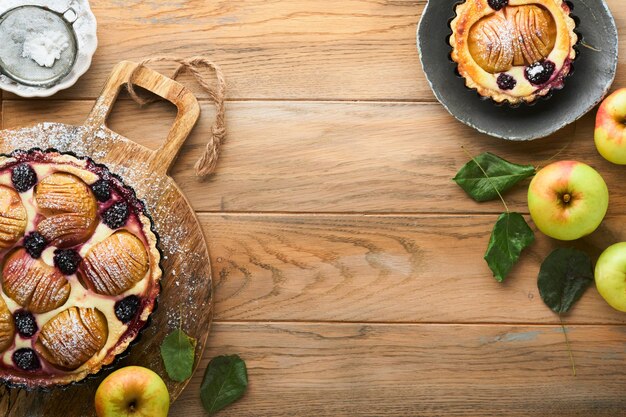 Szarlotka Ciasto z jabłkami i jeżynami Ozdobiony cukier puder na starym drewnianym stole Pyszny deser na jesienny lub zimowy obiad Deser z ciasta jesiennego Widok z góry
