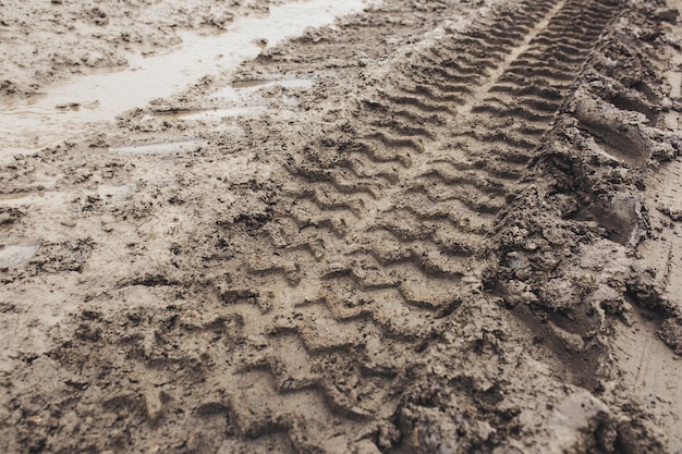 Szaro-brązowa tekstura z samochodowego śladu mokrej gliny i ziemi na drodze