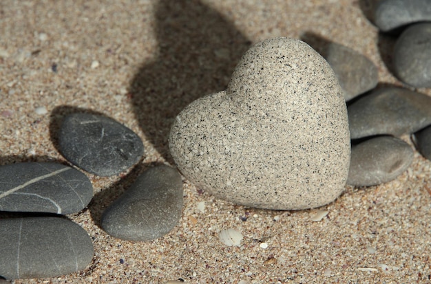 Szary kamień w kształcie serca na tle piasku