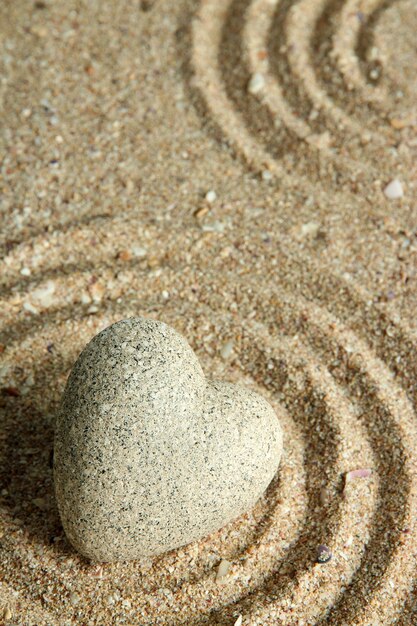 Zdjęcie szary kamień zen w kształcie serca na tle piasku