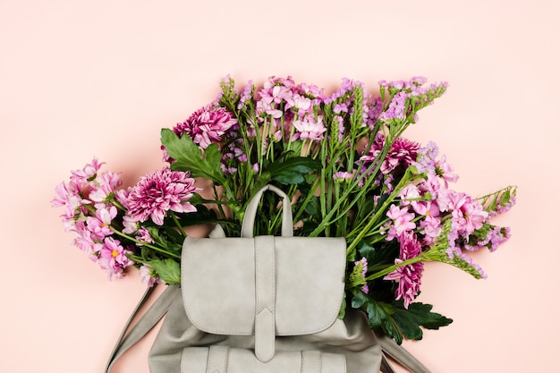 Szary plecak z pięknym bukietem kwiatów w środku.