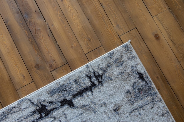 szary wzorzysty dywan leży na drewnianej podłodze