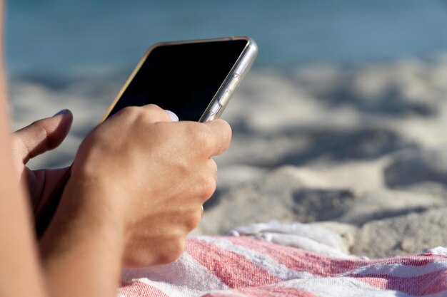 Szczegół Dłoni Kobiety Z Pomalowanymi Paznokciami Trzymającej Smartfon Na Plaży