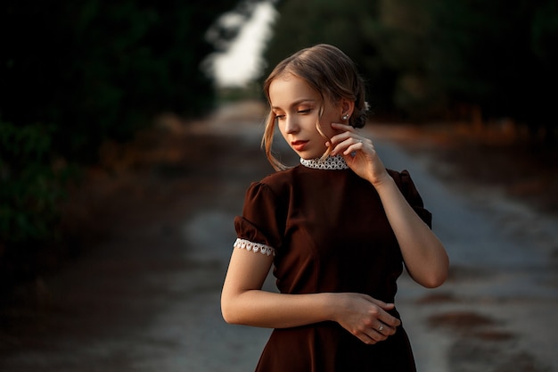 Szczegół portret młodej dziewczyny piękne w brązowej sukience w stylu retro na opuszczonej drodze.