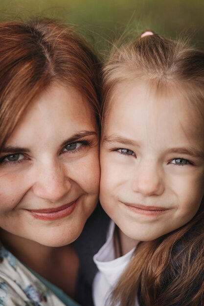 Szczegół portret młodej matki i córki w wieku szkolnym. szczęśliwe chwile razem. Pionowy