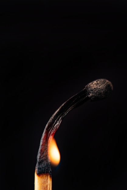 Szczegółowo płonąca zapałka widziana przez obiektyw makro na czarnym tle, selektywne ogniskowanie