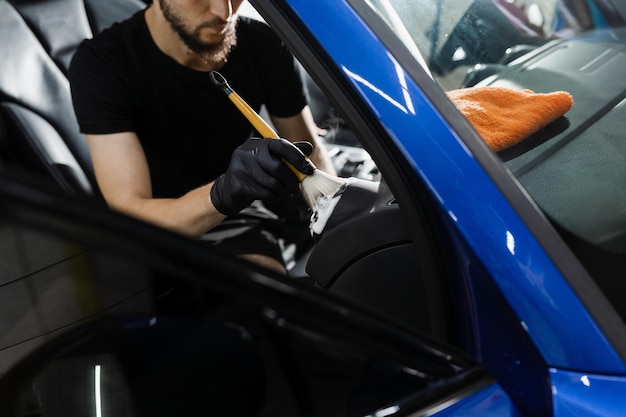 Szczegóły wnętrza samochodu System czyszczenia pianką i detergentem za pomocą pędzelka Pracownik w serwisie czyszczenia samochodu wyczyść samochód wewnątrz