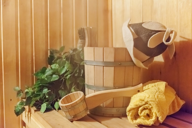 Szczegóły wnętrza Sauna fińska łaźnia parowa z tradycyjnymi akcesoriami do sauny umywalka brzozowa miotła miarka filcowy kapelusz ręcznik. Tradycyjna stara rosyjska łaźnia SPA Concept. Relaksująca koncepcja kąpieli w wiejskiej wiosce