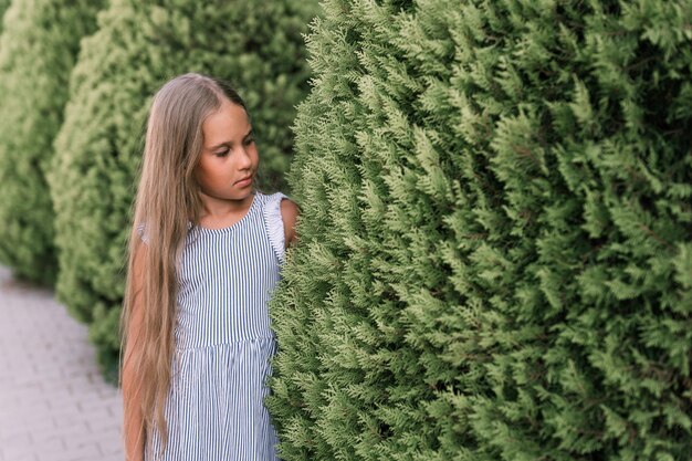 Szczera kaukaska szczęśliwa dziewczynka w wieku ośmiu lat z długimi blond włosami i zielonymi oczami na tle zielonych roślin podczas letnich wakacji podróży gen z koncepcja zdrowia psychicznego