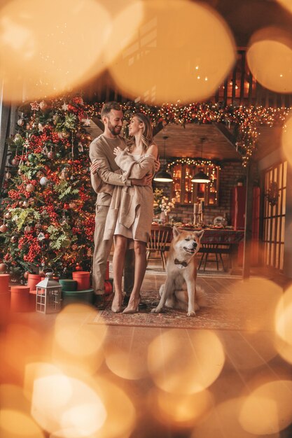 Szczere, autentyczne szczęśliwe małżeństwo spędza czas razem z japońskim psem w świątecznym domku