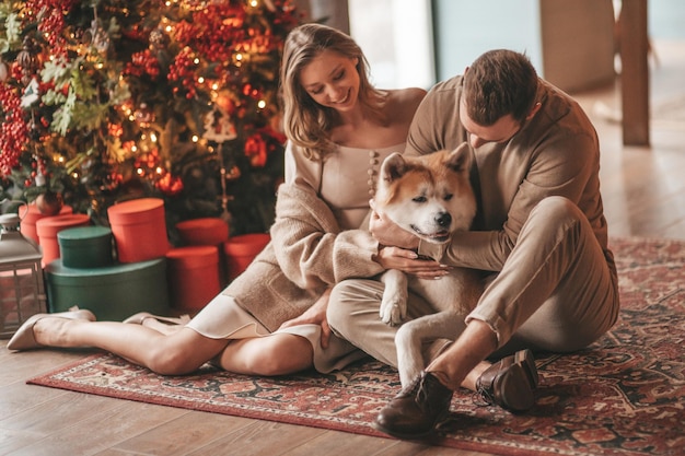 Szczere, autentyczne szczęśliwe małżeństwo spędza czas razem z japońskim psem w świątecznym domku