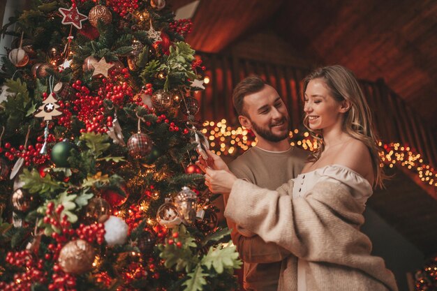 Szczere, autentyczne szczęśliwe małżeństwo spędzające razem czas w drewnianym domku udekorowanym świątecznie