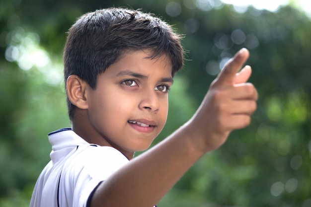 Szczere zdjęcie młodego indyjskiego chłopca z bliska twarz skierowaną w dal w plenerze