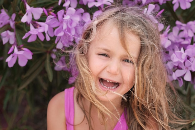 szczery portret dzieciaka dziewczyny śmiejącej się fioletowe letnie kwiaty w tle
