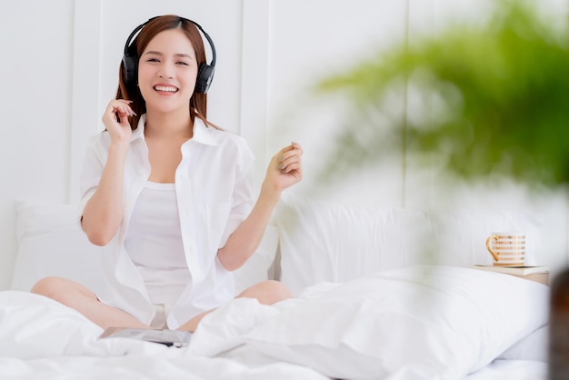 Szczęście azjatycka kobieta biała sukienka kostium cieszyć się tańcem słuchając muzyki z tłem sypialni słuchawek