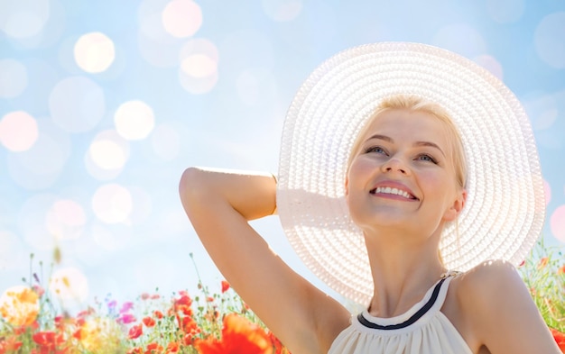 Zdjęcie szczęście, natura, lato, wakacje i koncepcja ludzi - uśmiechnięta młoda kobieta z zamkniętymi oczami w słomkowym kapeluszu na makowym polu
