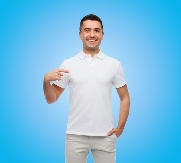 szczęście, reklama, moda, gest i koncepcja ludzi - uśmiechnięty mężczyzna w koszulce, wskazując palcem na siebie na niebieskim tle