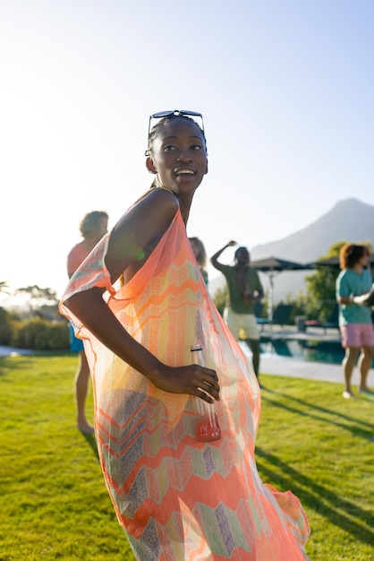 Szczęśliwa Afroamerykanka tańczy z przyjaciółmi na imprezie w ogrodzie. Styl życia, przyjaźń i impreza, lato, słońce, bez zmian.