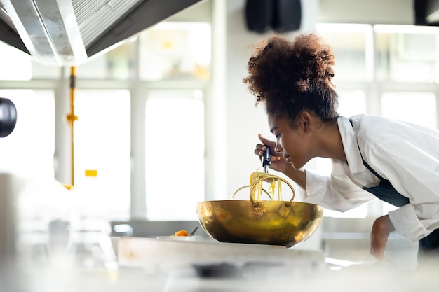 Szczęśliwa afroamerykańska kobieta stojąca z skrzyżowanymi ramionami podczas pracy jako szef kuchni w restauracji Klasa gotowania klasa kulinarna szczęśliwa młoda afrykańska kobieta studenci gotują w szkole gotowania