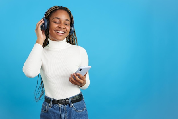 Szczęśliwa afrykańska kobieta słuchająca muzyki z telefonem komórkowym