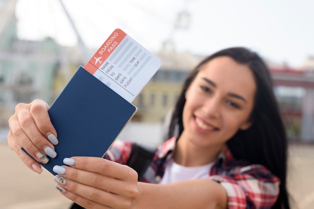 Zdjęcie szczęśliwa atrakcyjna kobieta pokazuje paszport i lotniczego bilet przy outdoors