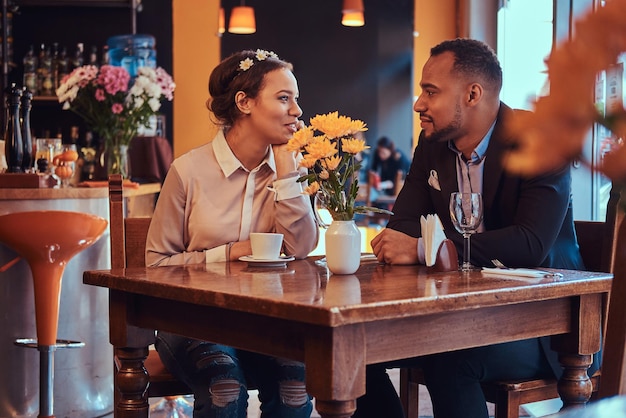 Szczęśliwa atrakcyjna zakochana para Afroamerykanów, która świetnie się bawi w restauracji na ich randkach, piękna para ciesząca się sobą.