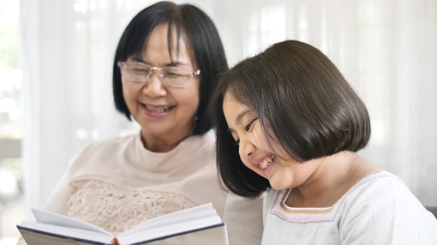 Szczęśliwa Azjatycka babcia i uroczej dziewczyny czytelnicza książka w domu wpólnie