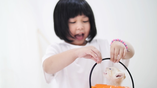 Szczęśliwa Azjatycka dziewczyna bawić się kryjówkę z małym figlarka inside dyniowym wiadrem