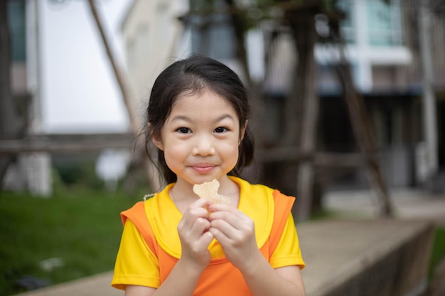 Szczęśliwa azjatycka dziewczyna w pomarańczowej sukience jedząca cukierki z galaretką