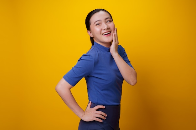 Szczęśliwa Azjatycka kobieta pokazując toothy uśmiech stojącej na żółto.