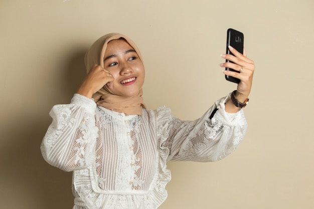 Szczęśliwa Azjatycka Kobieta W Hidżabie Z Telefonem Komórkowym Dokonywanie Selfie.