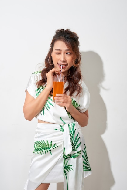 Szczęśliwa Azjatycka kobieta w letnie ubranie ze szklanką świeżego napoju soku owocowego