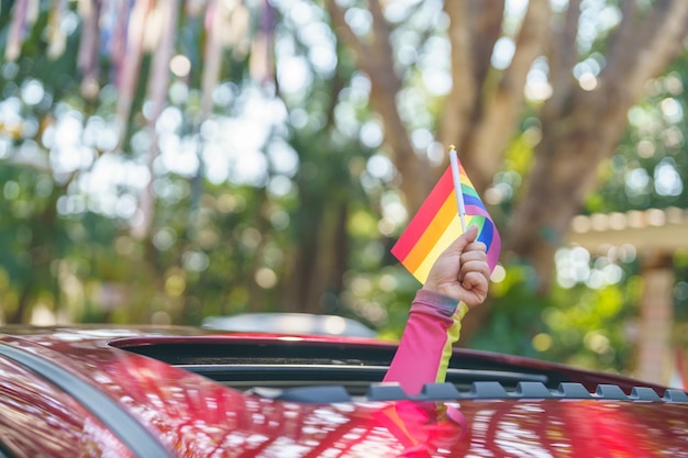 Szczęśliwa azjatycka kobieta wspiera paradę dumy LGBT w samochodzie z Rainbow of LGBTQ lub LGBTQIA