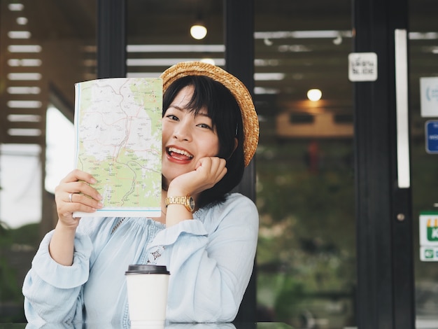 Szczęśliwa Azjatycka Kobiety Mienia Mapa W Rękach Przy Sklep Z Kawą.