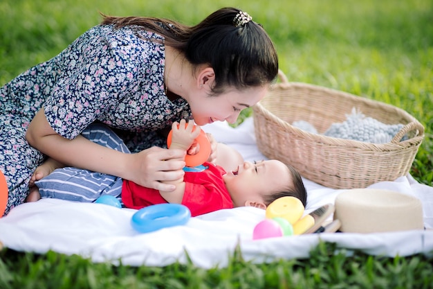 Szczęśliwa Azjatycka mama i mały synek bawią się podczas pikniku w parku na wakacjach rodzina bawią się i spędzają czas razem Szczęśliwa koncepcja rodziny