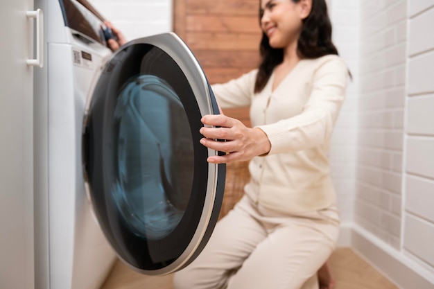 Szczęśliwa azjatycka młoda kobieta robi pranie w domowej koncepcji zdrowego stylu życia