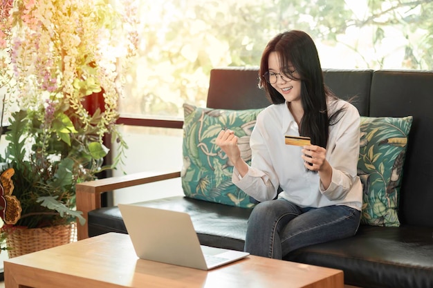 Szczęśliwa azjatycka młoda kobieta używająca laptopa do udanych zakupów online z kartą kredytową Koncepcja zakupów online