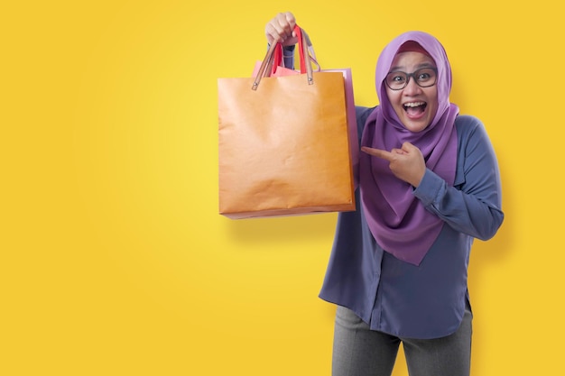 Szczęśliwa azjatycka muzułmańska kobieta przynosi torby na zakupy konsumpcjonistyczna koncepcja stylu życia