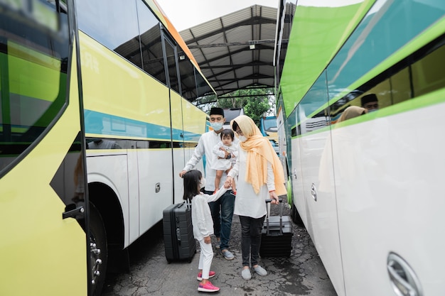 Szczęśliwa azjatycka muzułmańska wycieczka wakacyjna jeżdżąca autobusem wraz z rodziną w masce zapobiegającej rozprzestrzenianiu się wirusa