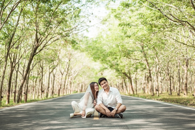 Szczęśliwa Azjatycka para w miłości na drodze z drzewo łukiem