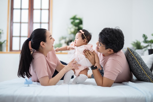 Szczęśliwa azjatycka rodzina siedzi w dziecięcej sypialni w domu