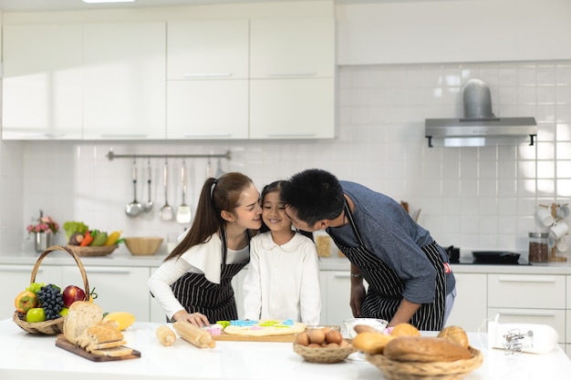 szczęśliwa azjatycka rodzina z córką robi ciasto przygotowujące do pieczenia ciasteczek