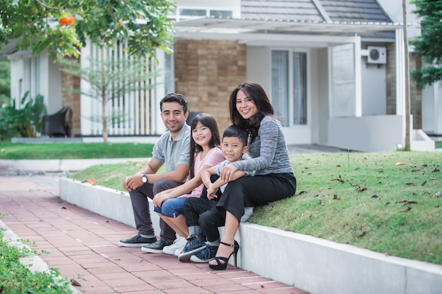 Szczęśliwa azjatykcia rodzina przed ich domem