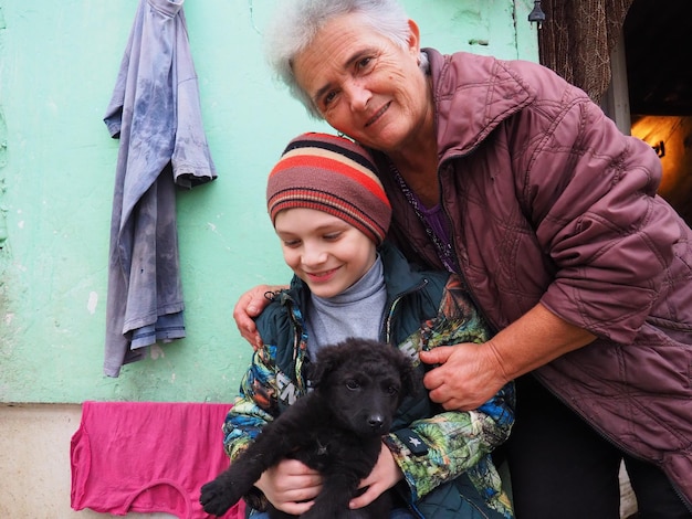 Szczęśliwa babcia i wnuk Czarny pies w ramionach dziecka Rodzina się śmieje