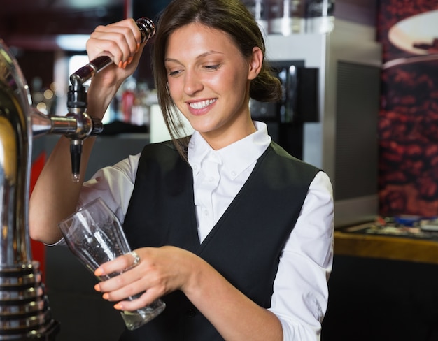 Szczęśliwa barmanka ciągnie kufel piwa