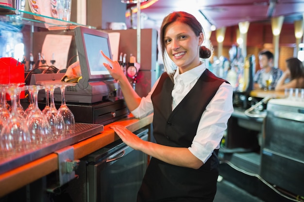 Szczęśliwa barmanka za pomocą ekranu dotykowego do w barze
